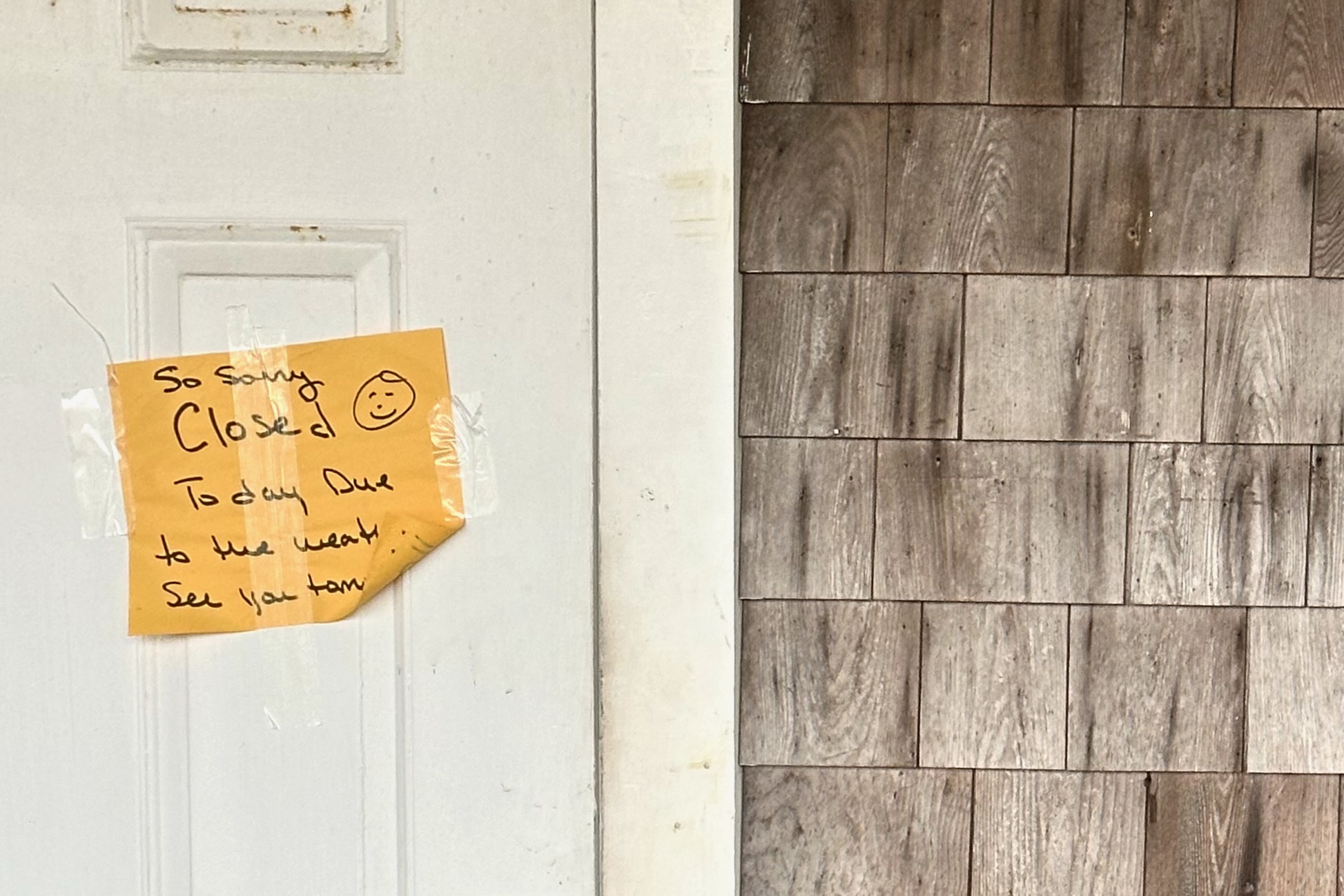 A note on a restaurant door says they are closed today due to the weather.